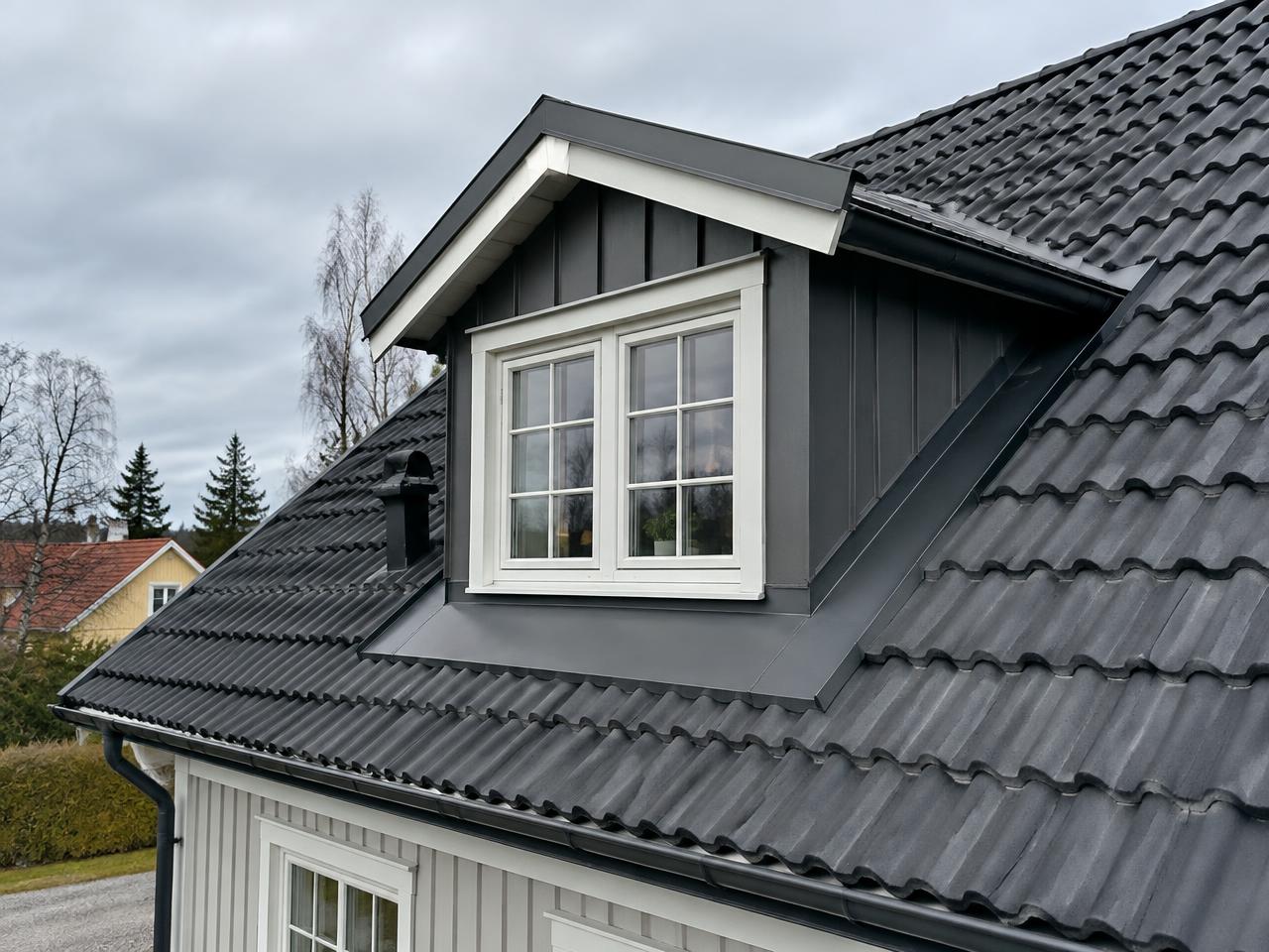 Svart tak med takkupa på vit villa